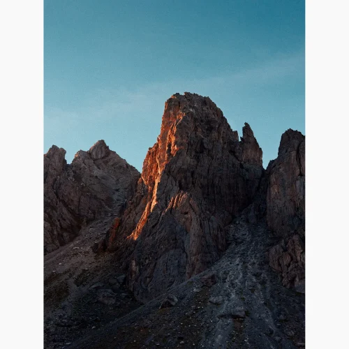 Tirage intitulé Coeur de la Montagne qui représente une montagne dans les Alpes près de Névache, avec une lumière orangée qui se reflète au centre de la roche.