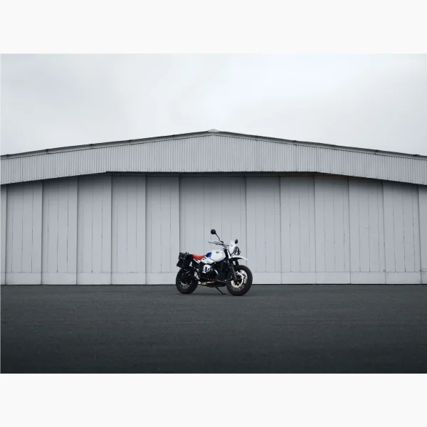 Tirage intitulé Flat Twin Hangar qui représente une BMW Nine T Urban GS devant un hangar d'avion.